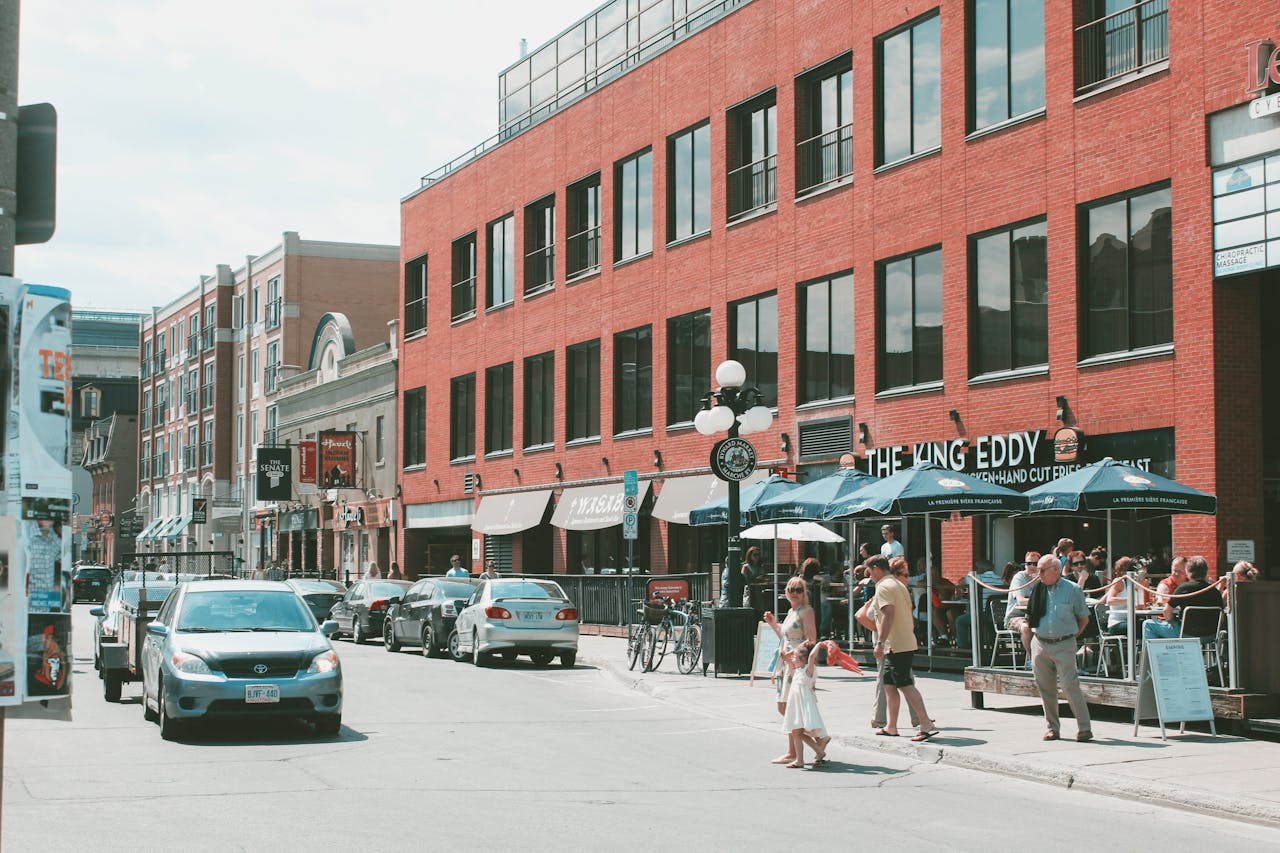 Vibrant street life in downtown Ottawa with cars, pedestrians, and outdoor cafes on a sunny day.